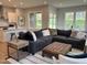 An open living space with a large sectional, a tufted leather ottoman, and kitchen featuring a white island at 230 Grading Stick Ct, Angier, NC 27501