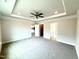 View of the bedroom with gray carpet, ceiling fan, tray ceiling, recessed lights and access to bath and walk-in closet at 328 Bishop Lane, Sanford, NC 27330