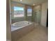 Modern bathroom boasting a soaking tub, walk-in glass shower, and large window overlooking the backyard at 52 Quail Point Cir, Clayton, NC 27520