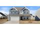 Two-story home with gray siding, stone accents, and a three-car garage at 1078 Gibson House Dr, Burlington, NC 27215