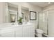 Well-lit bathroom featuring a double vanity, framed mirrors, and a glass-enclosed shower at 1585 Ivy Meadow Ln, Zebulon, NC 27597