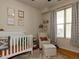 Cozy Bedroom featuring a crib, comfortable seating, and a bright window, perfect for a little one at 1001 Hillsborough St # 304, Raleigh, NC 27603