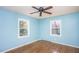 Bright bedroom with hardwood floors, blue walls, a ceiling fan, and dual windows at 3615 Octavia St, Raleigh, NC 27606