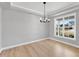 Bright and airy dining room featuring light wood floors, white walls, tray ceiling, and a modern chandelier at 443 Ravensworth Dr, Garner, NC 27529