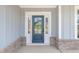 Close-up of a blue front door framed by white trim and brick base, creating a welcoming entrance at 443 Ravensworth Dr, Garner, NC 27529