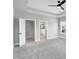 Main bedroom with tray ceiling, open bathroom entrance, and view of neighborhood at 443 Ravensworth Dr, Garner, NC 27529