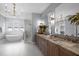 This bathroom is equipped with a double vanity, tub, shower, unique light fixture, and sleek gold hardware at 3723 Bellevue Rd, Raleigh, NC 27609