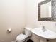 Clean bathroom with white sink, toilet, and decorative mirror at 713 Lake Artesia Ln, Fuquay Varina, NC 27526