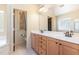 Bright bathroom featuring double sinks, wood cabinets, and a doorway leading to the toilet at 3009 Gentle Breezes Ln, Raleigh, NC 27614