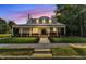 Inviting home with a metal roof, brick accents, and a welcoming front porch at dusk with lit windows at 505 S Magnolia Ave, Dunn, NC 28334