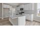 Well-lit kitchen featuring white cabinets, a large island with granite countertops, stainless steel appliances, and modern finishes at 236 Alden Way, Angier, NC 27501
