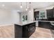 Modern kitchen island featuring black cabinetry with a quartz countertop and stainless steel appliances in the background at 6965 Us-401, Fuquay Varina, NC 27526