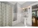 A charming bathroom featuring a pedestal sink, tiled walls, and a shower with a decorative curtain at 1015 Minerva Ave, Durham, NC 27701