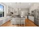 Bright kitchen boasts white cabinets, a central island with seating, and stainless steel appliances on hardwood floors at 1015 Minerva Ave, Durham, NC 27701