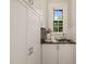 Practical mudroom area featuring a sink with granite countertop, white cabinetry, and natural light from the window at 1015 Minerva Ave, Durham, NC 27701