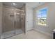 Tiled bathroom featuring a large shower with glass door, and a view through the window to the neighborhood at 15 Diamond Creek Dr, Zebulon, NC 27597
