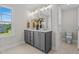 Bathroom featuring double sinks, a large mirror, a gray vanity, and a toilet behind an open door at 15 Diamond Creek Dr, Zebulon, NC 27597