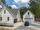 View of a white house with a carport, detached garage and a sleek black car on a concrete driveway at 205 Purslane Dr, Franklinton, NC 27525