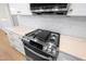 Close up of a modern stainless steel range with white cabinets and a white tiled backsplash at 205 Purslane Dr, Franklinton, NC 27525