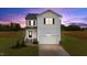 Two-story home showcasing a white exterior, black shutters, and a neatly manicured lawn against a colorful dusk sky at 35 Diamond Creek Dr, Zebulon, NC 27597
