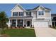 Charming two-story home featuring a manicured lawn, a two-car garage, and a welcoming front porch with stone accents at 120 Berry Mill Ln # 129, Raleigh, NC 27603