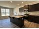 Modern kitchen features dark cabinets, stainless steel appliances, granite countertops, and a large island at 259 Johnson Ridge Way, Four Oaks, NC 27524
