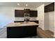 Modern kitchen features dark cabinets, stainless steel appliances, granite countertops, and a large island at 259 Johnson Ridge Way, Four Oaks, NC 27524