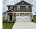 Two-story home featuring stone accents, brown siding, a two-car garage, and manicured landscaping at 320 Bishop Ln, Sanford, NC 27330