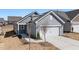 Attractive exterior showcasing a gray home with a spacious two-car white garage, set against a landscaped yard at 1829 Hydrangea Way, Fuquay Varina, NC 27526