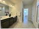 Bright bathroom featuring double vanity sinks, tiled floors, and a view to the bedroom and the shower at 225 Bering Cir, Angier, NC 27501