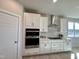Gourmet kitchen with stainless steel appliances, white cabinets, and tile backsplash at 225 Bering Cir, Angier, NC 27501