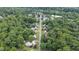 An aerial view of a neighborhood with mature trees, houses, and a street, all set against a bright sky at 2416 Glencoe St, Burlington, NC 27217