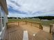 Wooden deck overlooks a field with neighborhood homes and scattered trees under a partly cloudy sky at 111 Demascus Way # 021, Four Oaks, NC 27524