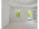 Bright bedroom featuring plush carpet, tray ceiling, a window, and a door leading to the outside at 9216 Leaning Post Rd # 447, Wake Forest, NC 27587