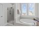 Spa-like bathroom featuring a soaking tub, glass-enclosed shower, and natural light from large windows at 120 W Weatherford Dr, Angier, NC 27501