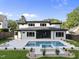 Expansive backyard featuring a modern home with a pool and spa, set against a backdrop of lush green lawn and mature trees at 662 Manchester Dr, Raleigh, NC 27609