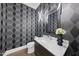 Stylish powder room with modern vanity, elegant mirror, and patterned wallpaper for a unique design at 662 Manchester Dr, Raleigh, NC 27609