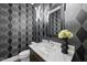 Chic powder room featuring geometric wallpaper, a marble countertop, and a sleek mirror at 662 Manchester Dr, Raleigh, NC 27609