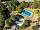Aerial view showcases an outdoor pool, tennis court, and community amenities in a lush wooded setting at 3105 Cone Manor Ln, Raleigh, NC 27613