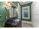 Bathroom boasts green floral wallpaper, patterned tile flooring, and dark wood vanity with black countertop at 3105 Cone Manor Ln, Raleigh, NC 27613