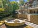 Outdoor fire pit with stone seating near the pool is surrounded by lush trees and landscaping at 3105 Cone Manor Ln, Raleigh, NC 27613