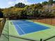 A fenced-in, well-maintained tennis court with blue and green playing surface is surrounded by lush trees at 3105 Cone Manor Ln, Raleigh, NC 27613
