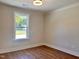 Bright bedroom featuring beautiful laminate floors, a modern light fixture, and a large window at 1011 Lemon Dr, Durham, NC 27705