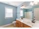 Bathroom with a double sink vanity with blue walls, a large mirror, and natural light from the window at 2024 Stanchion St, Haw River, NC 27258