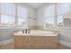 The soaking tub features tile surround, and plenty of natural light with the large windows surrounding it at 2024 Stanchion St, Haw River, NC 27258