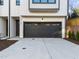 A well-lit, black garage door adds modern curb appeal to this white, two-story townhome at 811 Maple Berry Ln # 101, Raleigh, NC 27607
