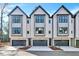 Modern townhomes boast a crisp white exterior, dark trim, and attached garages for convenient parking at 811 Maple Berry Ln # 105, Raleigh, NC 27607