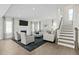 Bright living room featuring a fireplace, hardwood floors, and an open staircase at 8841 Tartan Clan Dr, Willow Springs, NC 27592