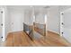 Well-lit hallway with hardwood floors, wood and black railing, and white doors leading to other rooms at 55 Firefly Ln, Louisburg, NC 27549