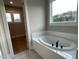 Elegant bathroom featuring a soaking tub with tile surround, patterned tile floor, and a window at 274 Golden Leaf Farms Rd, Angier, NC 27501